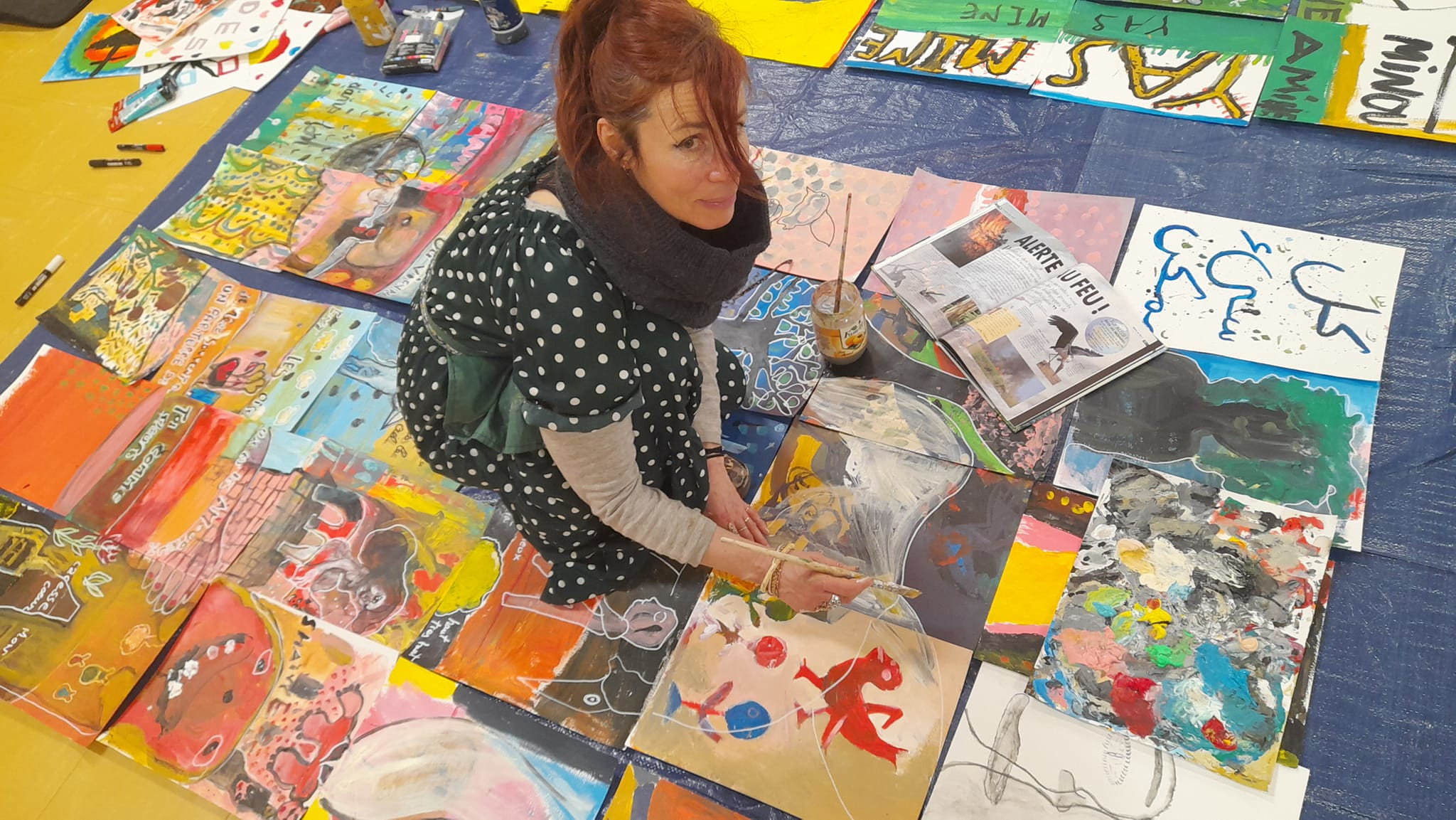 Caroline Dahyot, assemblant des dessins d'enfants pour la fresque MATTOMUNDUS